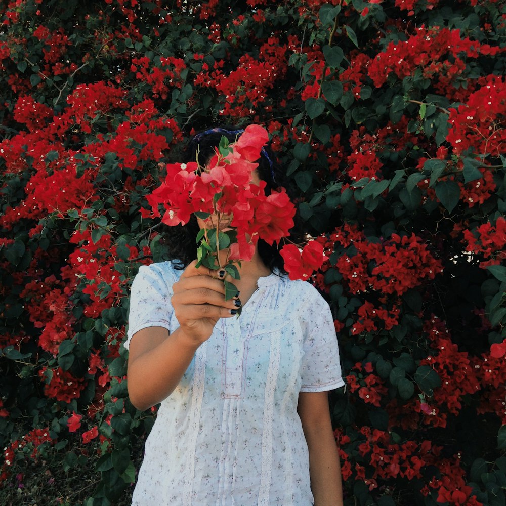 woman in white dress holding red flowers