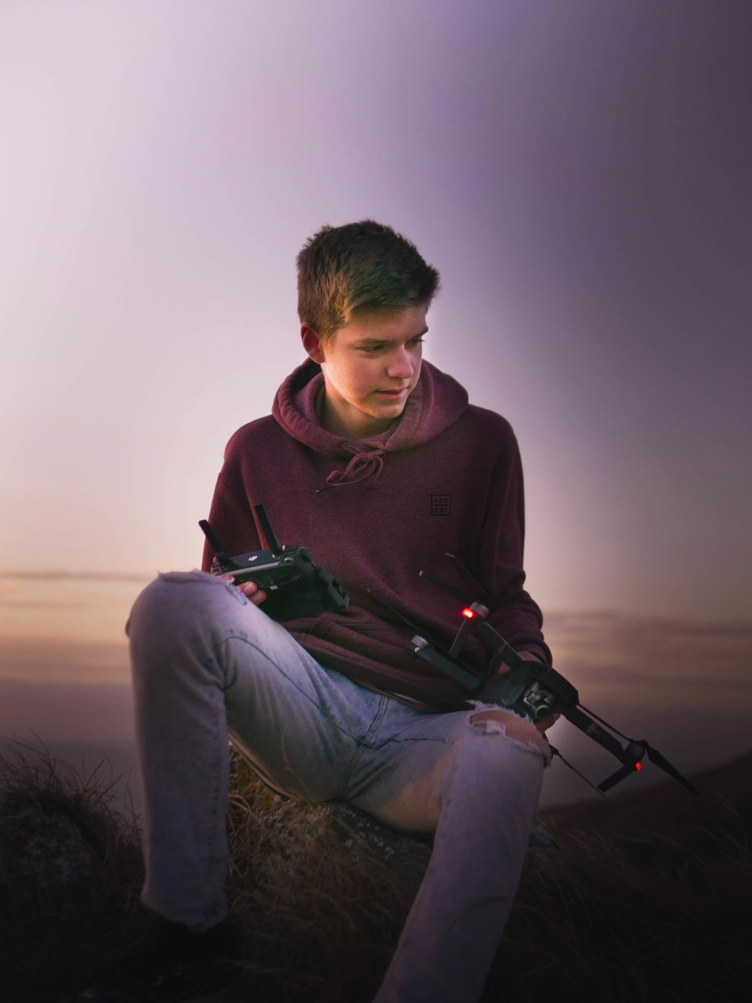 man in red hoodie and gray pants sitting on rock