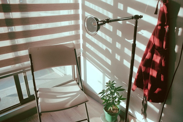 A sunlit garden corner featuring a foldable chair beside a rattan plant basket and a glowing solar lantern.