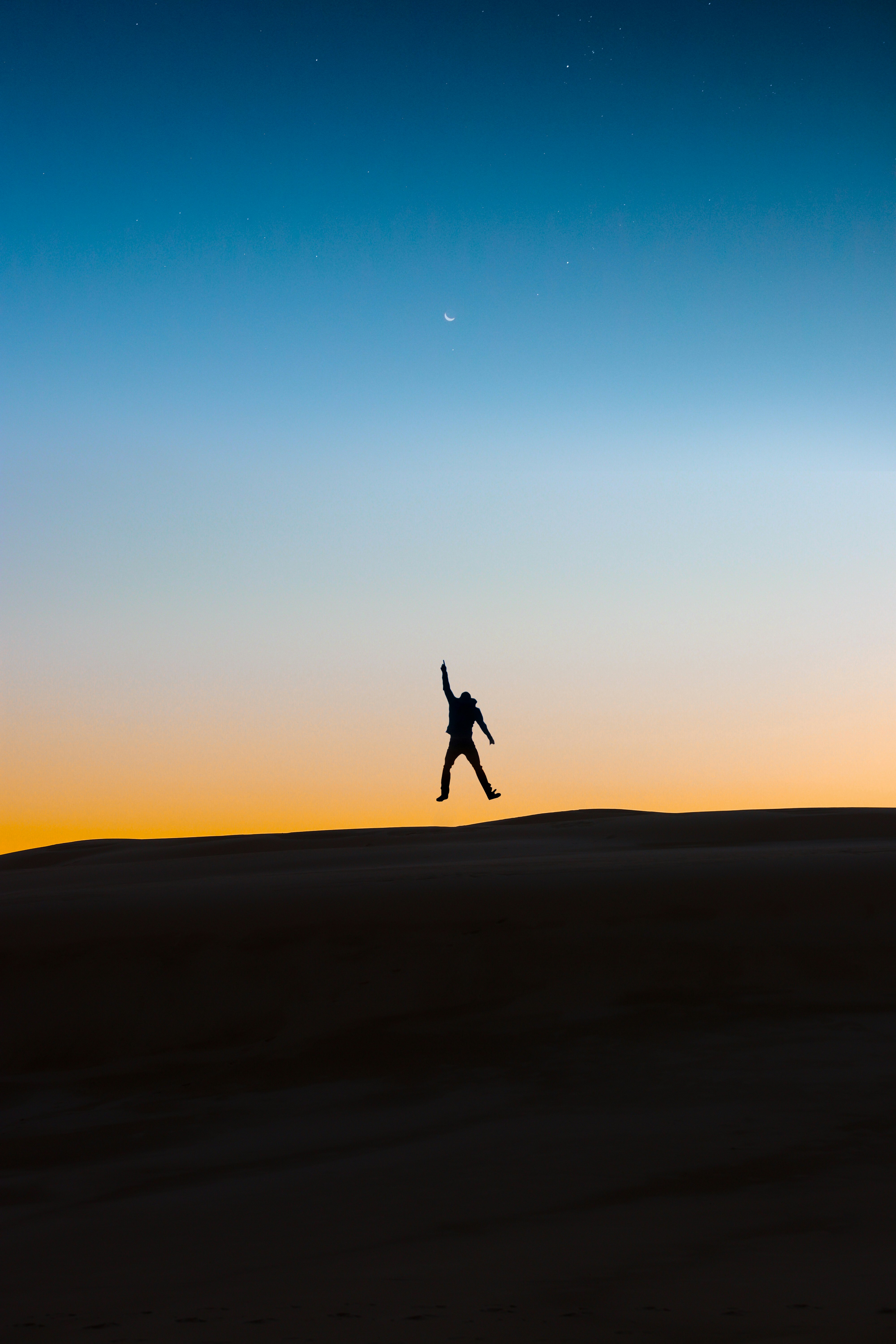 silhouette of person jumping on brown sand during sunset