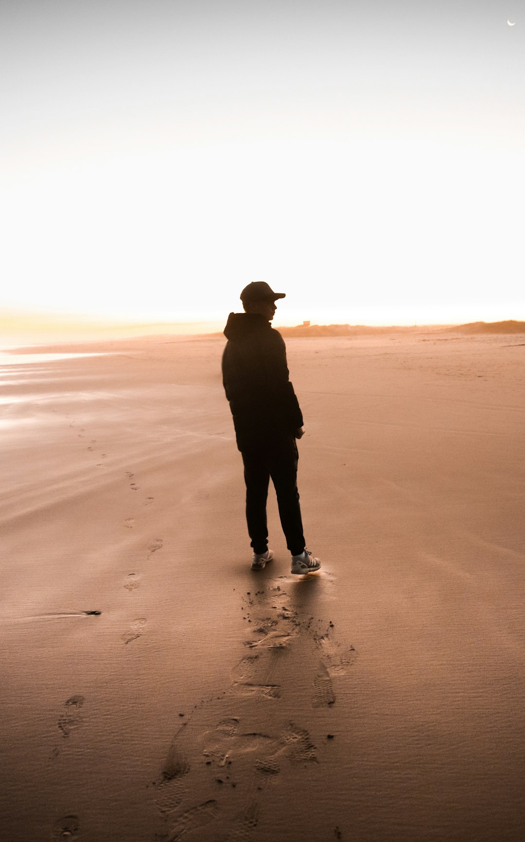 silhouette of man standing on beach during daytime