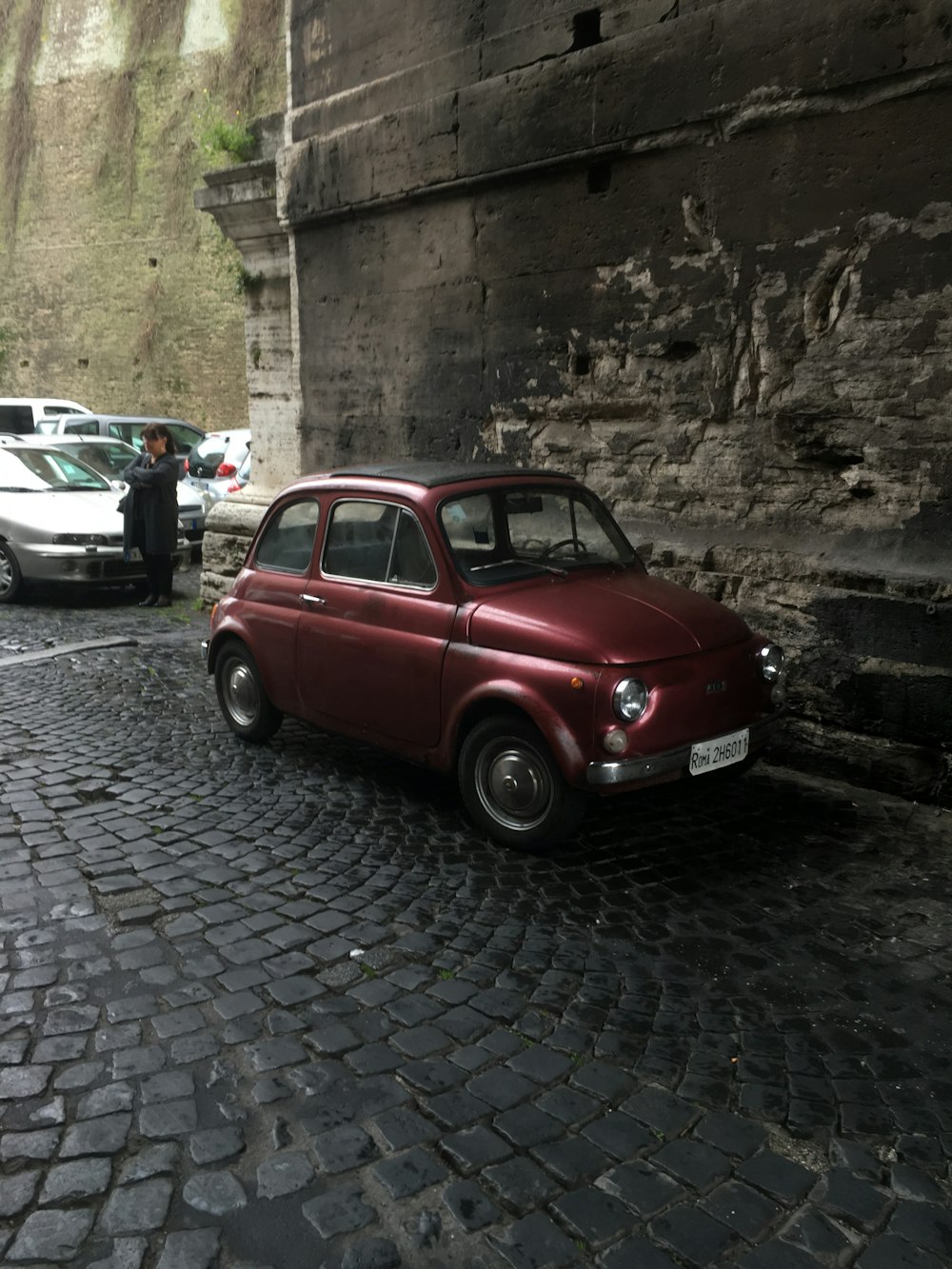 red volkswagen beetle parked beside white sedan during daytime
