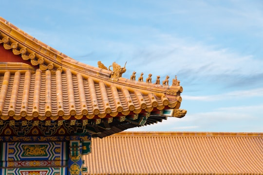 brown and black concrete building under white clouds during daytime in Forbidden City China
