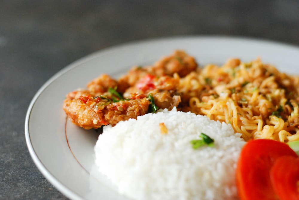 fried rice with sliced tomato and green vegetable on white ceramic plate