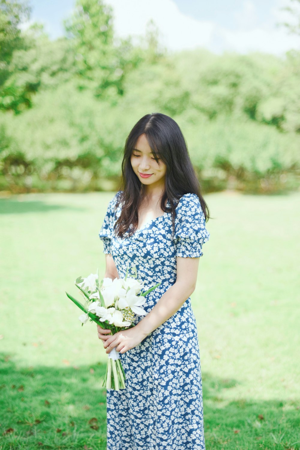woman in blue and white floral dress holding white flower bouquet
