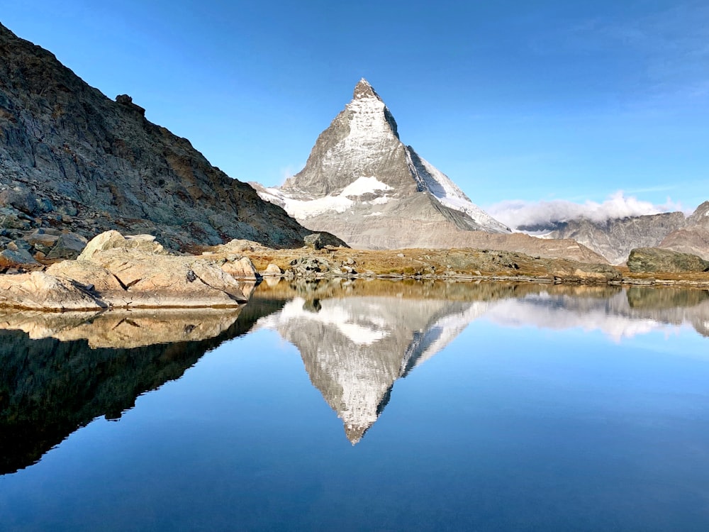 snow covered mountain near lake under blue sky during daytime