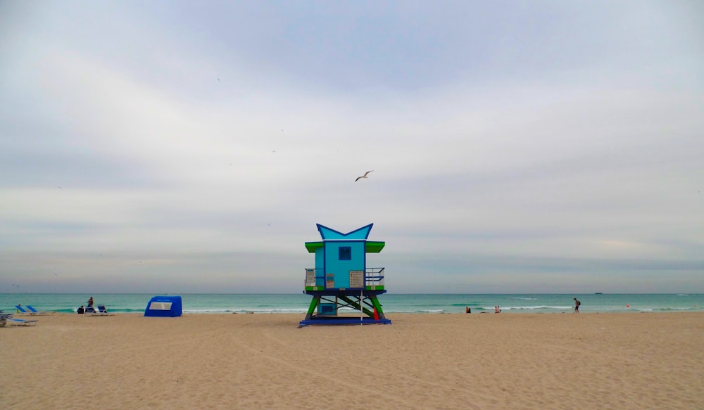 green lifeguard house on beach shore during daytime