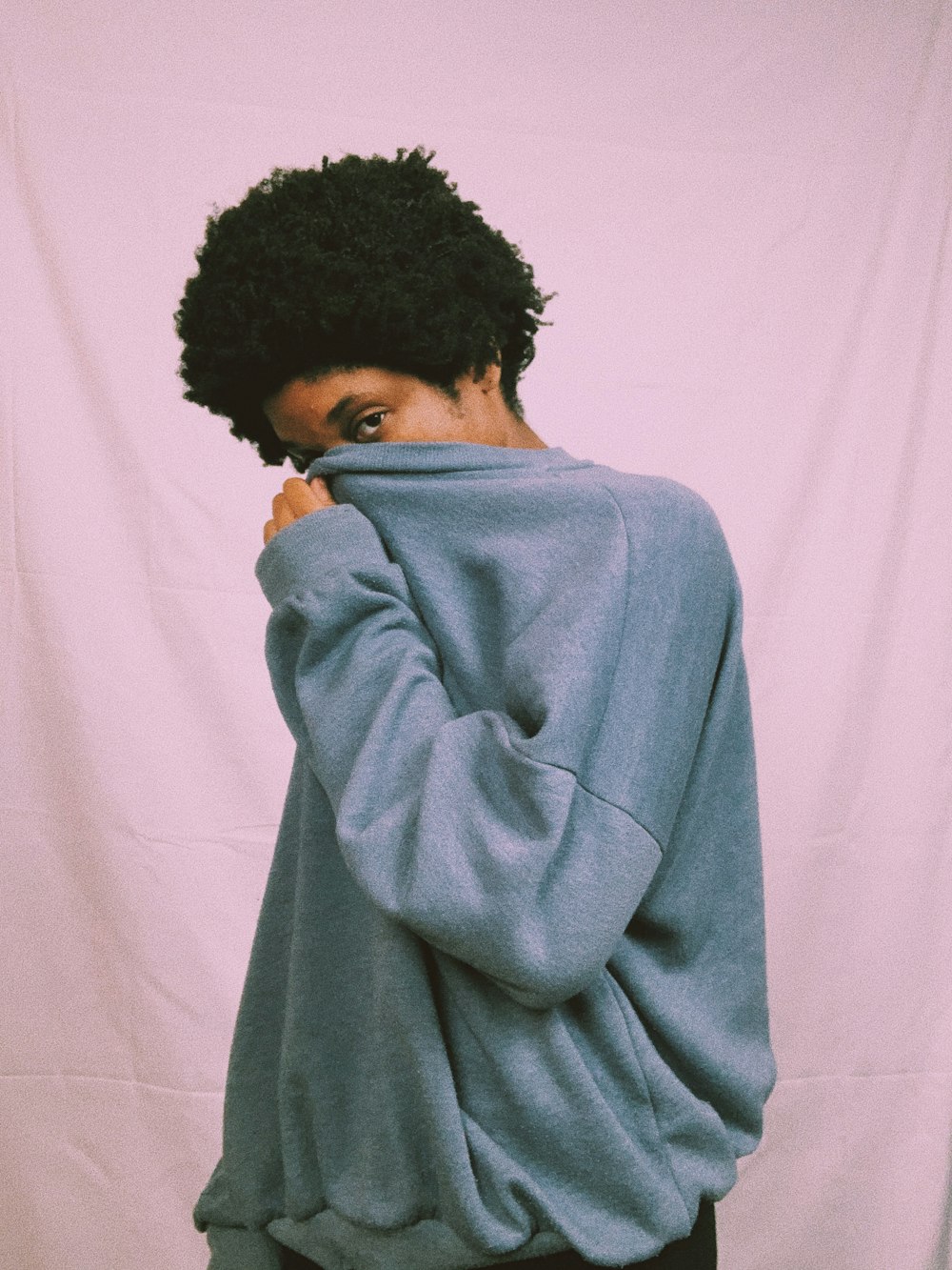 woman in gray sweater standing near white curtain