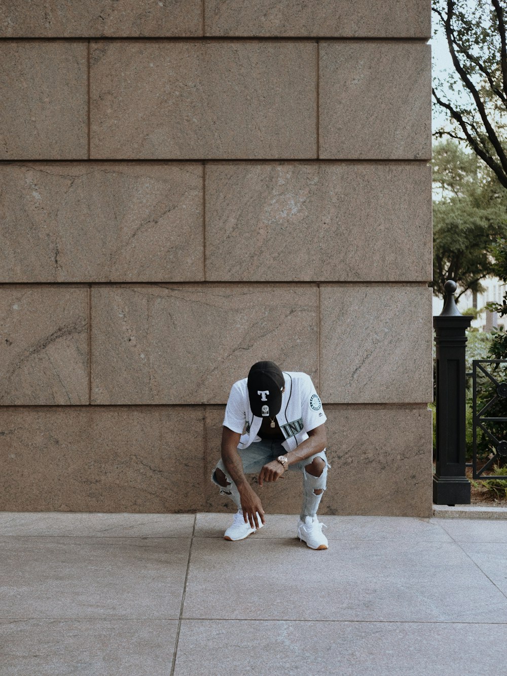 man in black t-shirt and white shorts sitting on concrete wall during daytime