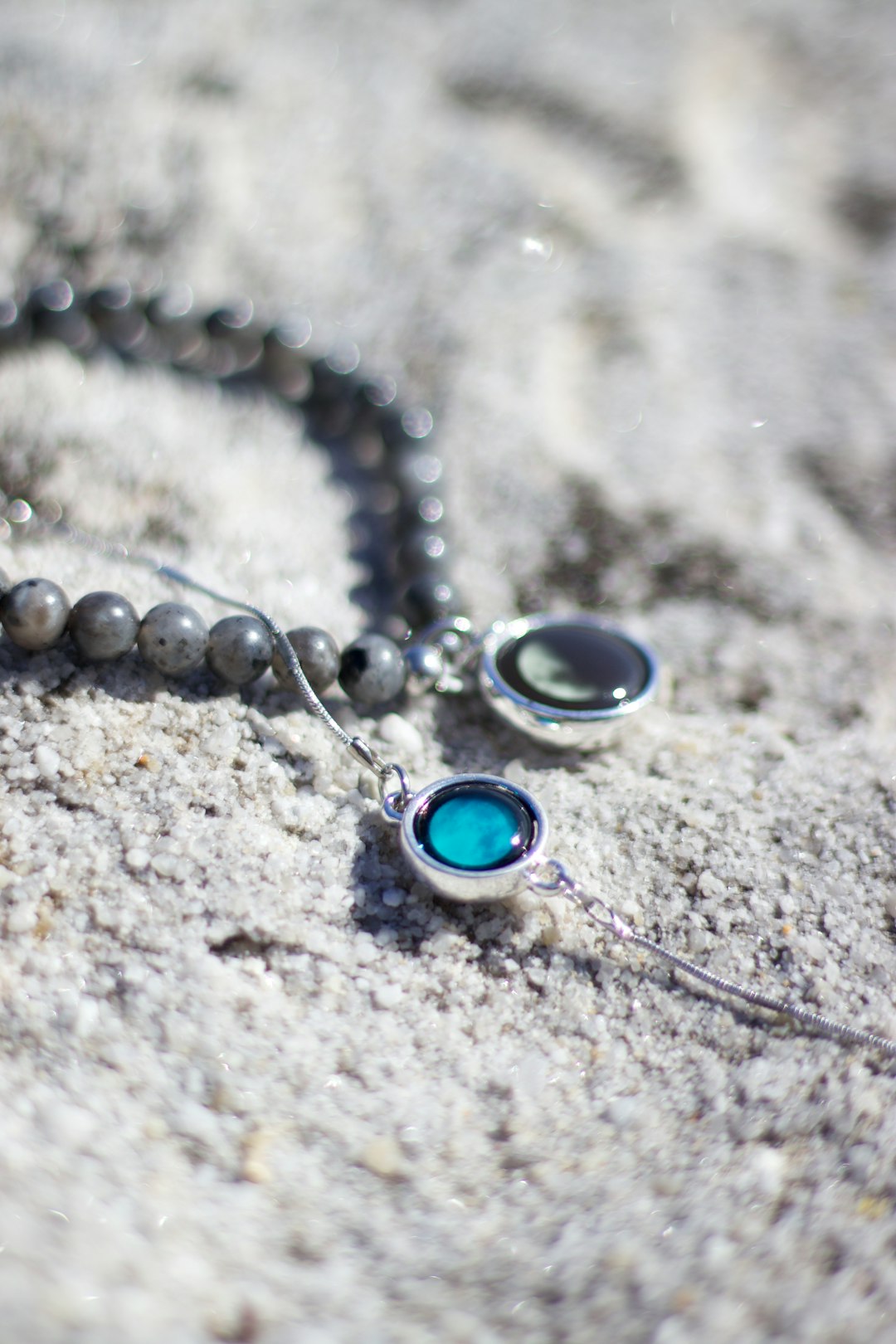 silver blue gemstone necklace on gray sand