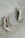 A pair of elegant white high-heeled shoes are placed alongside a wedding invitation. The invitation is adorned with delicate floral and leaf designs, accompanied by small decorative pearls and beads.