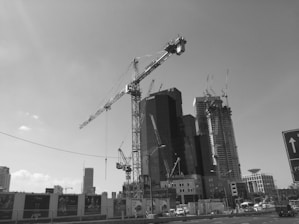 Construction workers collaborating on a building site with cranes in the background.