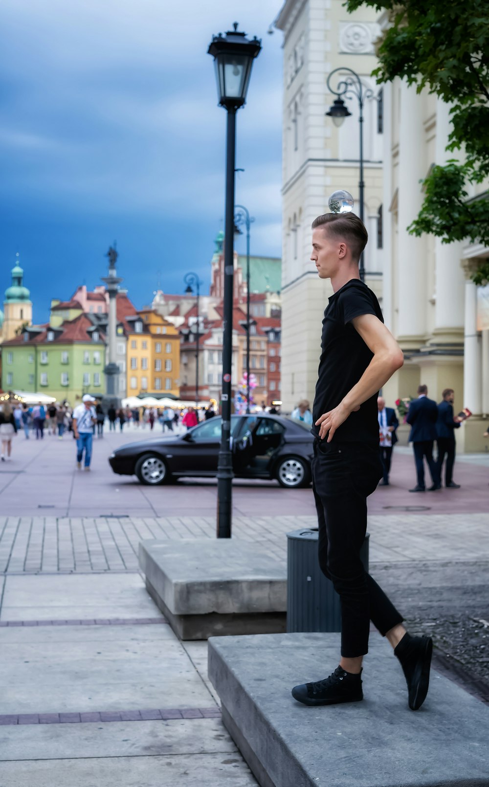 man in black t-shirt and black pants standing on sidewalk during daytime