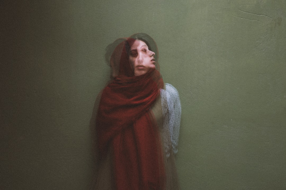 woman in red hijab standing beside green wall