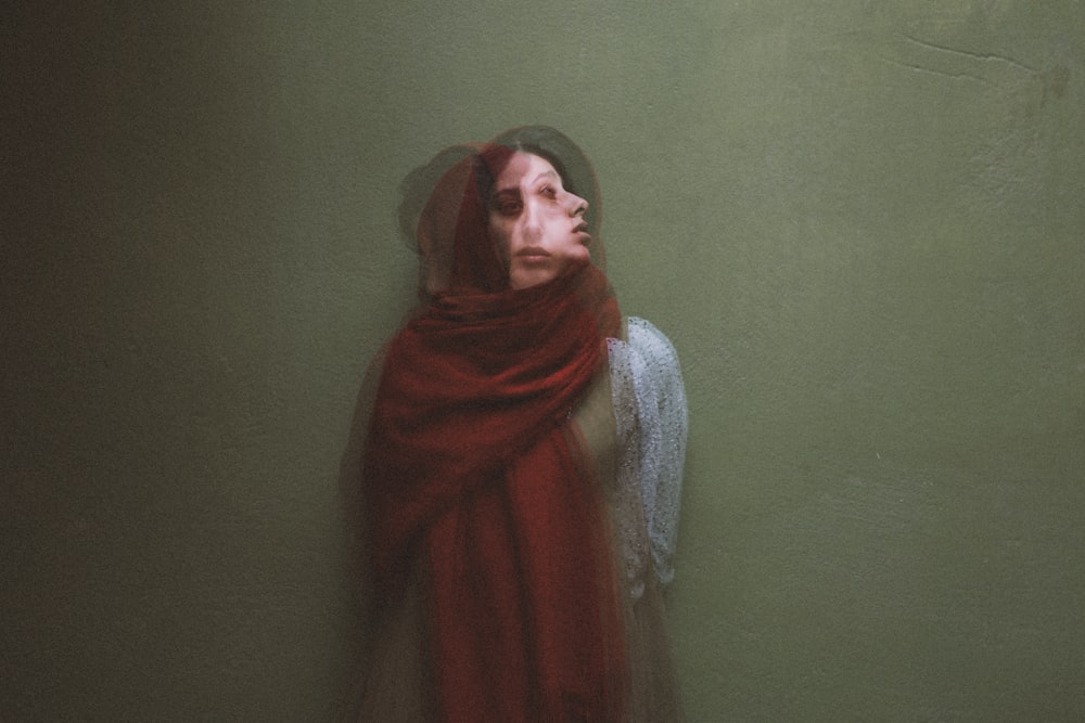 woman in red hijab standing beside green wall