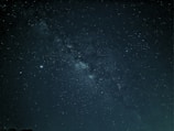 A captivating view of the night sky filled with countless stars and a visible section of the Milky Way galaxy. The dark canvas is dotted with bright star clusters and subtle variations in star brightness, presenting a mesmerizing and vast cosmic panorama.
