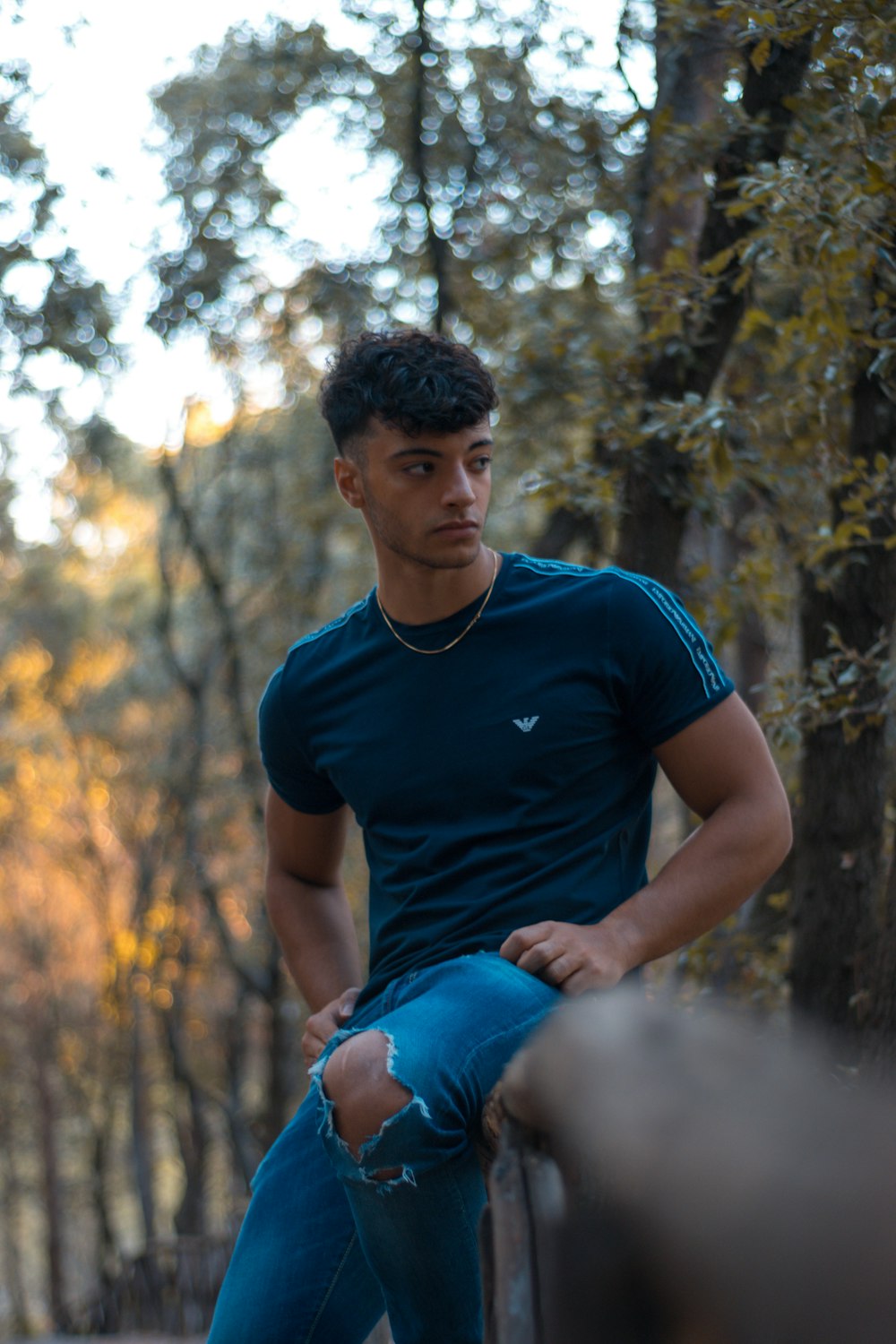 man in blue crew neck t-shirt and blue denim shorts sitting on ground during daytime