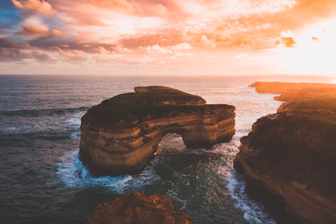 brown rock formation on sea during sunset