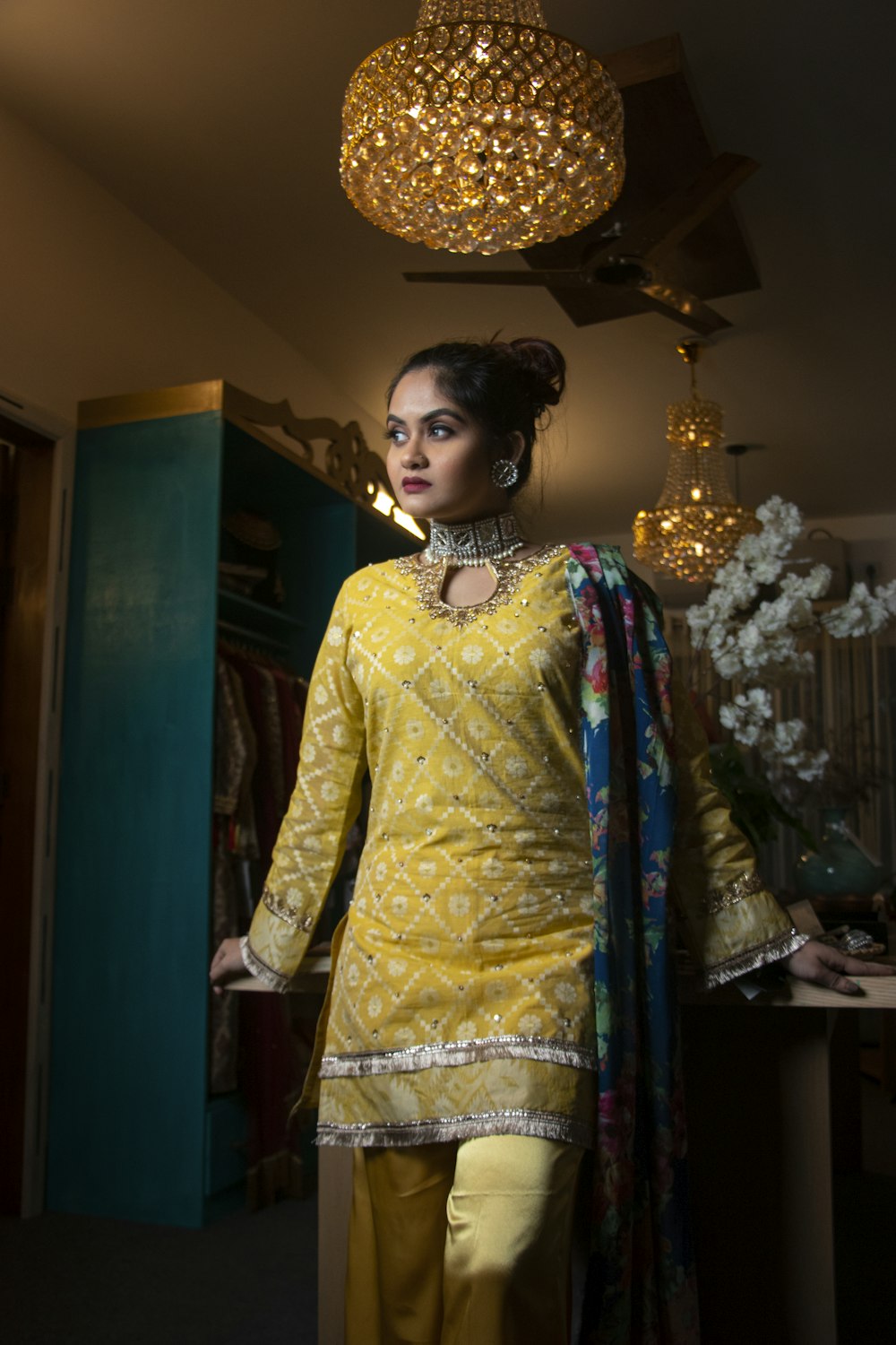 woman in yellow and white long sleeve dress standing near brown wooden cabinet