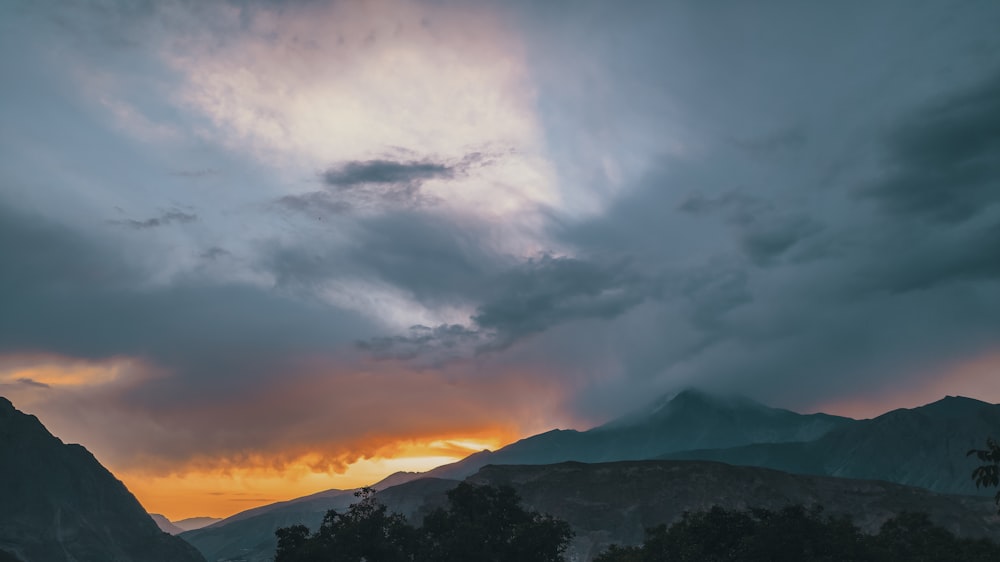 silhouette de montagne sous ciel nuageux au coucher du soleil