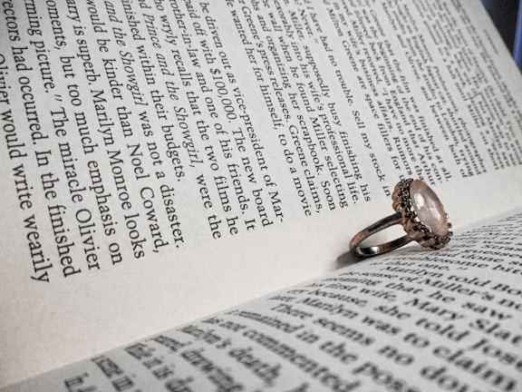 A charming ring with a gemstone centerpiece resting on a vintage book page.