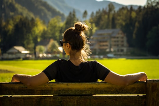 woman in black crew neck t-shirt sitting on brown wooden bench during daytime in Zgornje Jezersko Slovenia