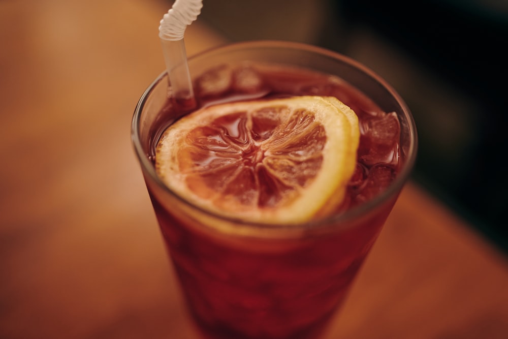 clear drinking glass with red liquid and sliced lemon