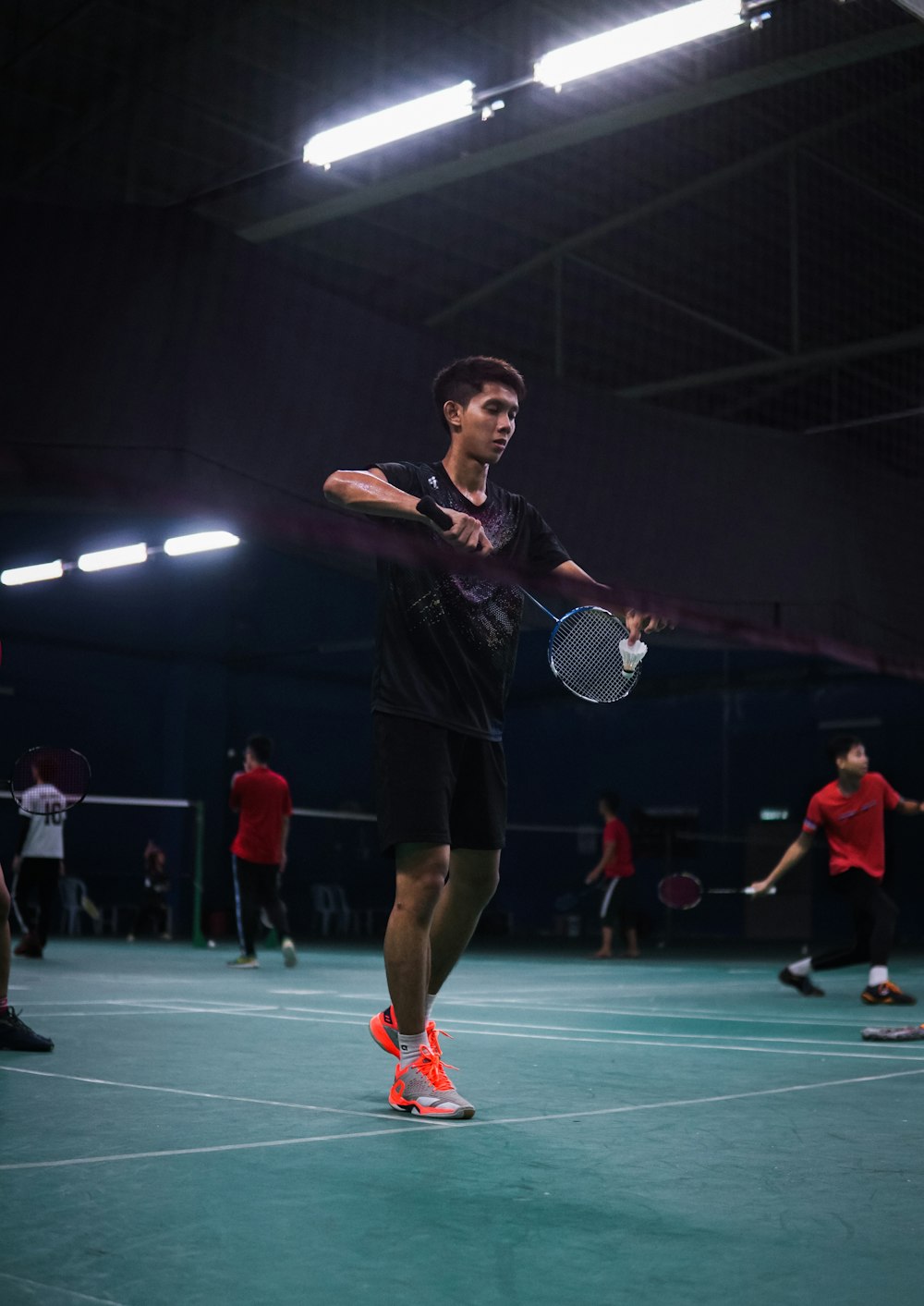 man in black t-shirt and red shorts standing on green floor