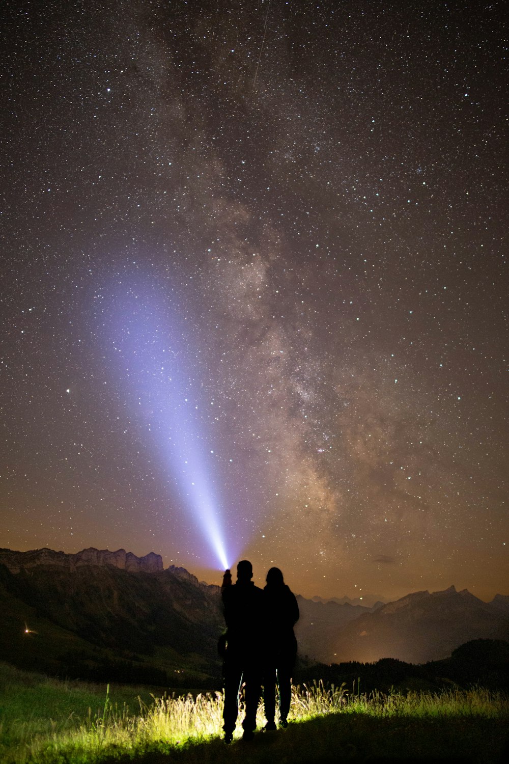 silhouette of 2 person sitting on rock under starry night
