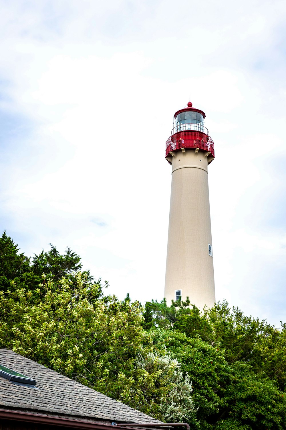 Phare blanc et rouge sous des nuages blancs pendant la journée