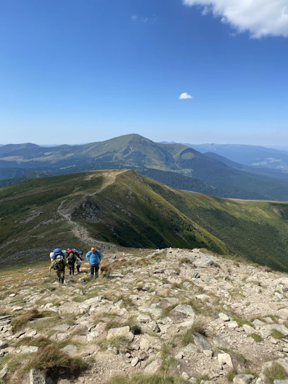 A group of hikers pausing on a rocky desert trail under a clear blue sky, sharing a moment of connection.