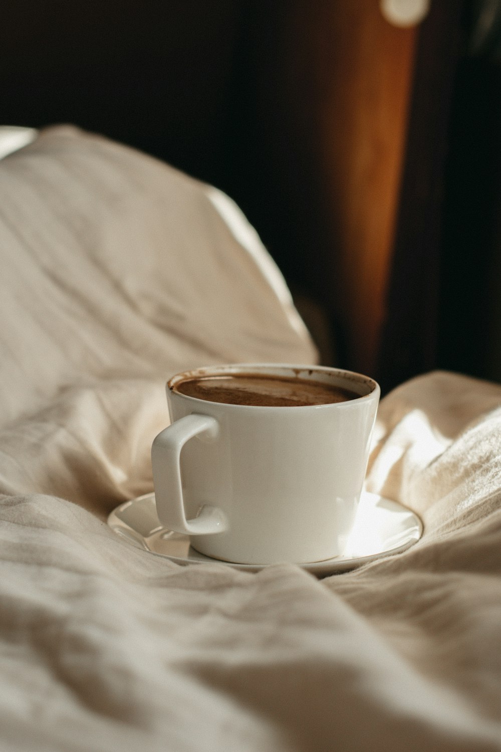 white ceramic mug on white textile