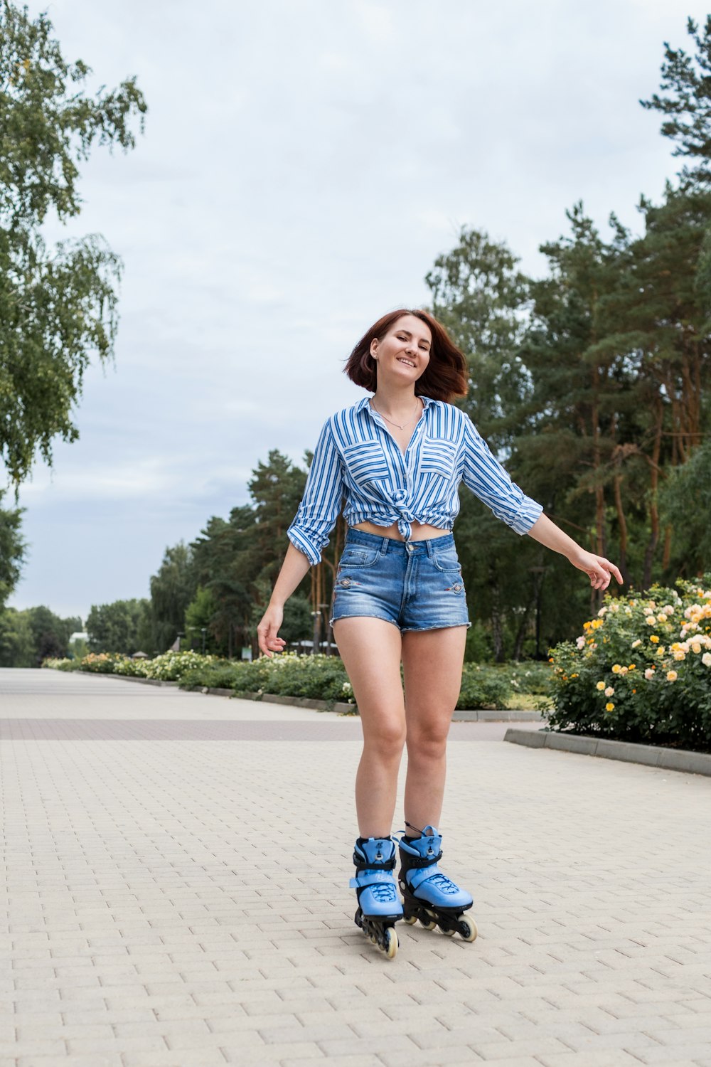 woman in blue and white plaid dress shirt and blue denim shorts standing on gray concrete