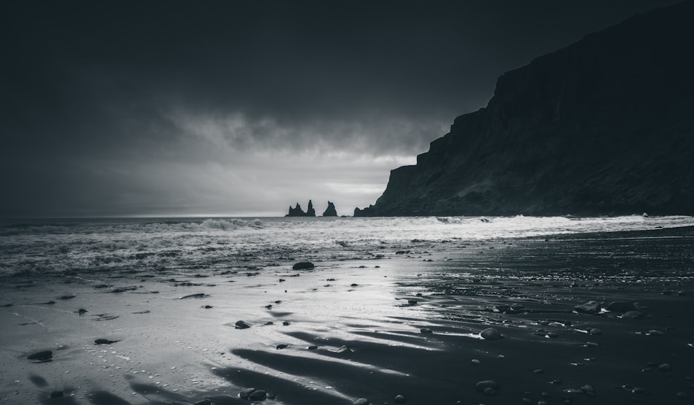 grayscale photo of rock formation on sea