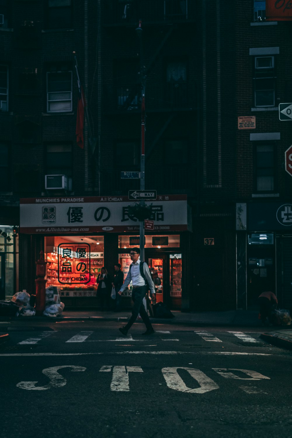 man in black jacket walking on pedestrian lane during night time