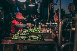 man in red jacket and red hat standing in front of green vegetable