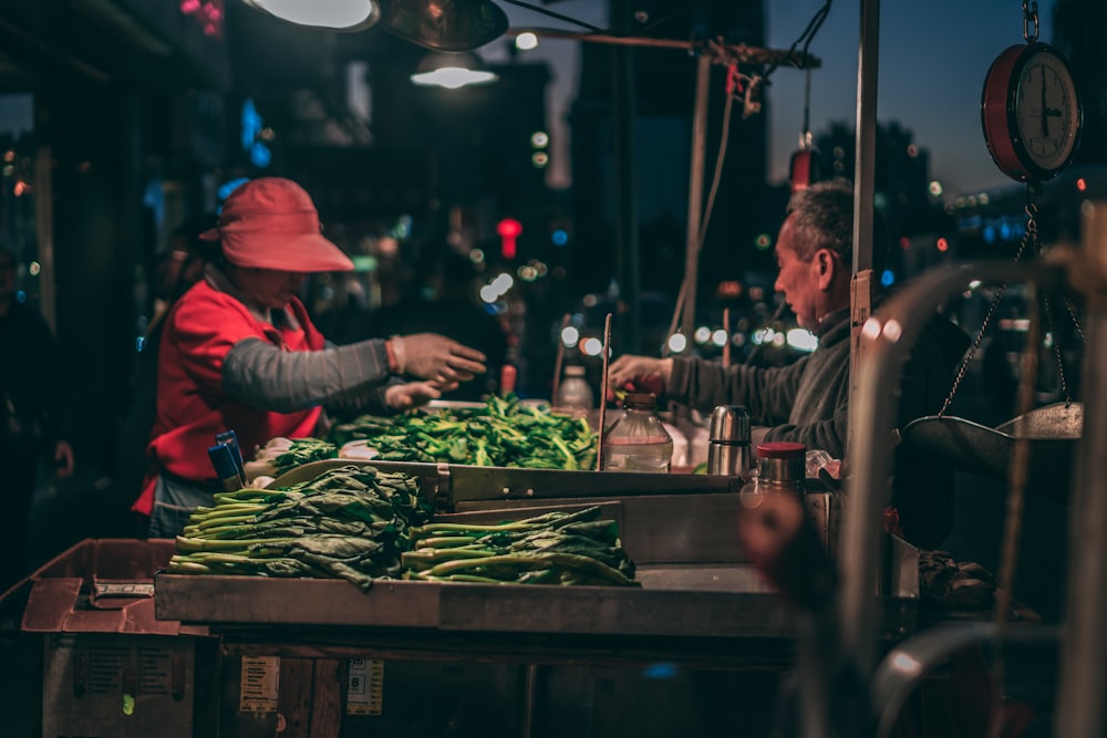 man in red jacket and red hat standing in front of green vegetable