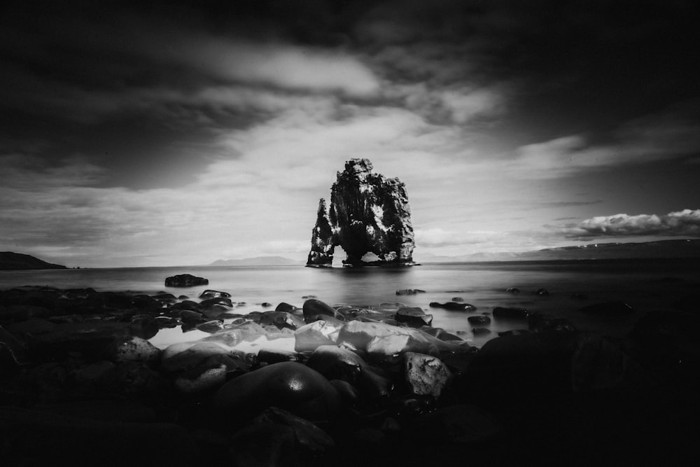 grayscale photo of rocks on seashore