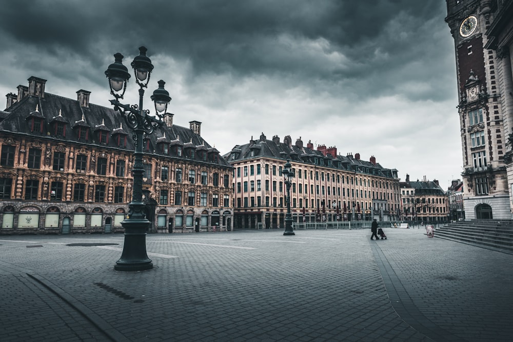 people walking on street near brown concrete building under gray clouds during daytime