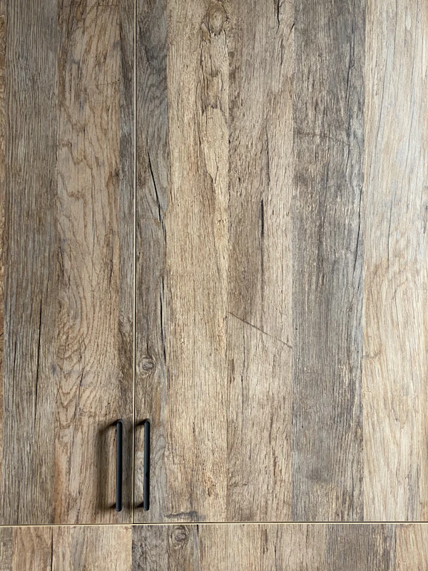 LVP vs. Hardwood Flooring: black metal door hinge on brown wooden surface