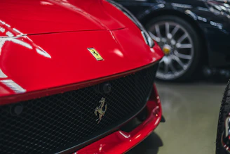 Close-up of a Ferrari F8's aggressive front grille with Dolomite peaks in the background.