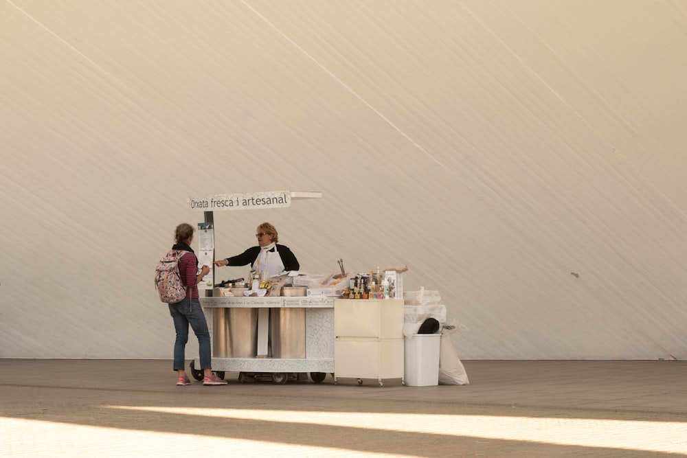 two women standing at a table with a sign on it