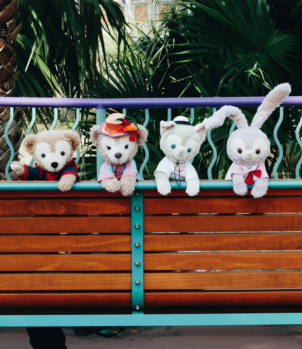 2 white dog plush toys on brown wooden bench