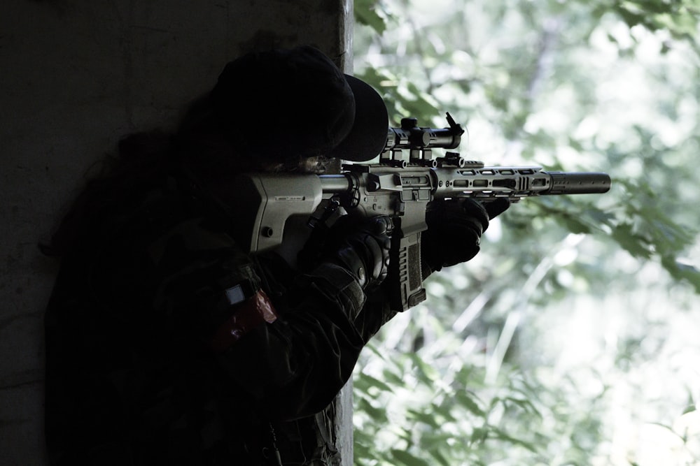 Hombre con chaqueta negra sosteniendo un rifle negro