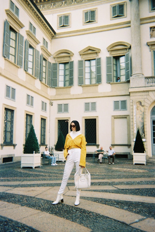 woman in yellow long sleeve shirt and white skirt walking on street during daytime in Indro Montanelli Park Italy