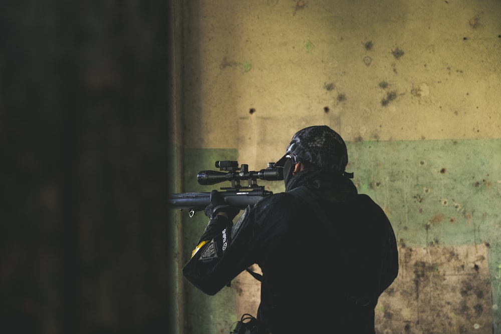 man in black jacket holding rifle