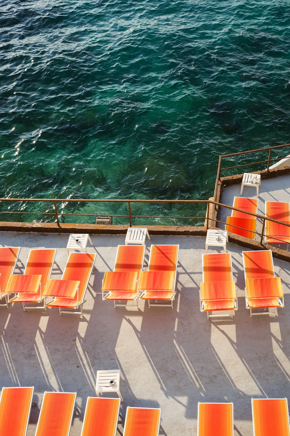 Sillas de plástico naranja y blanco en el muelle