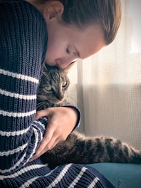 person holding brown tabby cat