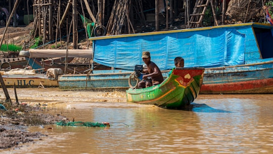 man in black shirt riding on green and yellow boat during daytime in Kampong Phluk Cambodia
