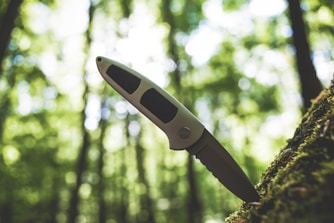 white and black handle knife stuck in a tree